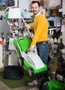 Smiling guy deciding on best lawnmower in garden equipment shop