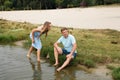 A smiling guy and a girl are resting on the banks of a picturesque river. A man is sitting on the beach Royalty Free Stock Photo