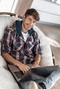 Smiling guy with a laptop sitting in a chair Royalty Free Stock Photo