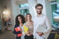 Smiling guy with a laptop and two girls with notebooks.