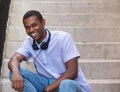 Smiling guy sitting on steps outside with headphones Royalty Free Stock Photo