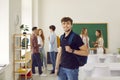 Portrait of smiling guy student with bag in audience looking at camera during break.