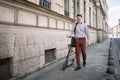 Smiling guy walking on sidewalk with electric scooter Royalty Free Stock Photo