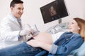 Smiling gynecologist providing ultrasonic pregnant patient monitoring at work Royalty Free Stock Photo