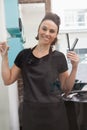 Smiling hairdresser holding hair equipment