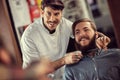 Smiling hairdresser shaving with scissors