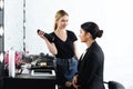 smiling hairstylist with hair spray and businesswoman