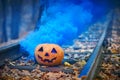 Smiling halloween pumpkin with bright blue smoke on the rails in the forest Royalty Free Stock Photo