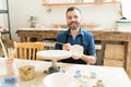Artist Painting Earthenware With Paintbrush In Pottery Workshop