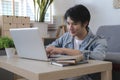 Smiling handsome asian man sitting on floor in living room and using laptop computer Royalty Free Stock Photo