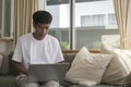 Smiling handsome asian man sitting on floor in living room and using laptop computer Royalty Free Stock Photo