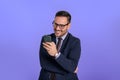 Smiling handsome business manager text messaging over smart phone while standing against blue background. Portrait of cheerful Royalty Free Stock Photo