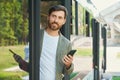 Smiling male passenger with cellphone, getting off city bus. Royalty Free Stock Photo