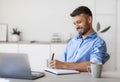 Smiling Handsome Businessman Taking Notes To Notepad At Workplace In White Office Royalty Free Stock Photo