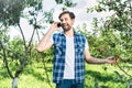 smiling handsome farmer talking by smartphone in apple garden