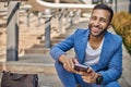 Smiling handsome Indian business man sitting on outdoor city stairs