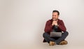 Smiling handsome male entrepreneur with hands clasped looking away while sitting with crossed legs. Young sales executive working Royalty Free Stock Photo