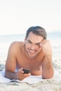 Smiling handsome man on the beach holding his cellphone Royalty Free Stock Photo