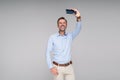 Smiling handsome man using smartphone, taking selfie or talking online with friends, isolated on gray background Royalty Free Stock Photo