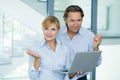 Smiling handsome, mature businessman and confident businesswoman, working on laptop computer in modern office building Royalty Free Stock Photo