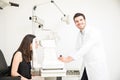 Smiling handsome optician checking young woman eyes Royalty Free Stock Photo