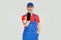 Smiling handsome plumber, repairman looking at camera, smiling and holding mobile phone with empty screen. Handyman