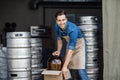 Smiling handsome strong millennial worker guy in apron pulls out big can with ingredients Royalty Free Stock Photo