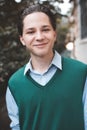 Smiling handsome teen boy student 17-18 year old wear knit vest and shirt outdoors. Happy teenager outdoor on city street. Royalty Free Stock Photo