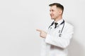 Smiling handsome young doctor man isolated on white background. Male doctor in medical gown, stethoscope pointing index Royalty Free Stock Photo