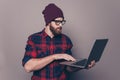 Smiling handsome young man in cap and glasses holding modern laptop Royalty Free Stock Photo