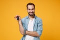 Smiling handsome young man in casual blue shirt posing isolated on yellow orange wall background, studio portrait Royalty Free Stock Photo