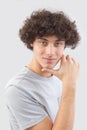 Smiling and handsome a young man with curly hair he looks into the camera with his blue eyes, his hands on his face, a portrait of Royalty Free Stock Photo