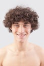 Smiling and handsome, a young man with curly hair, he looks into the camera with his blue eyes, a portrait of a guy with a bare Royalty Free Stock Photo