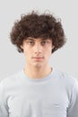 smiling and handsome a young man with curly hair he looks into the camera with his blue eyes, portrait of guy isolated against a Royalty Free Stock Photo