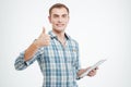 Smiling handsome young man using tablet and showing thumbs up Royalty Free Stock Photo