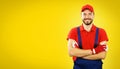 Smiling handyman with arms crossed on yellow background with copy space