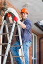 Portrait of smiling handyman climbing on stepladder to repair street lamps