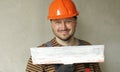 Smiling handyman repairman worker in overalls and protective orange helmet holds big putty knife for plastering concrete Royalty Free Stock Photo