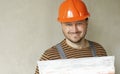 Smiling handyman repairman worker in overalls and protective orange helmet holds big putty knife for plastering concrete Royalty Free Stock Photo