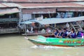 Smiling and happiness tourists take traditioanal long tail boat to visit the Ampawa floating market