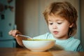 Smiling happy adorable baby eating fruit mash in the kitchen. The child in the kitchen at the table eating. Cheerful Royalty Free Stock Photo