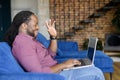 Smiling and happy African-American guy makes video call on the laptop Royalty Free Stock Photo