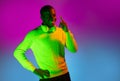 Smiling happy African handsome man posing isolated over gradient magenta yellow neon background.