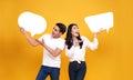 Smiling happy Asian couple holding blank speech bubbles on yellow background. Royalty Free Stock Photo