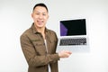 Smiling happy asian man holding laptop with mockup in his hands on a white studio background Royalty Free Stock Photo