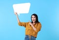 Smiling happy asian woman holding blank speech bubble and with empty space for text on blue background Royalty Free Stock Photo