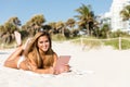 Smiling happy asian woman lying on beach using tablet computer Royalty Free Stock Photo