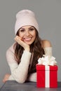 Smiling and happy, beautiful young woman in winter clothes with a red Christmas gift box on a gray background. The girl Royalty Free Stock Photo