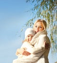 Smiling happy blonde woman and girl hugging outdoor in park against blue sky. Royalty Free Stock Photo