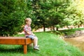 Smiling happy boy sitting on bench near lake. Summer time weekend mood. Royalty Free Stock Photo